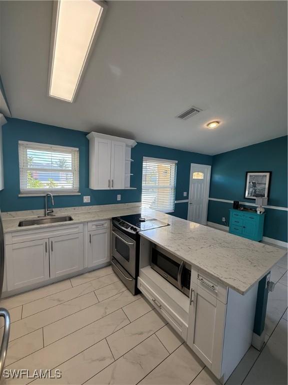 kitchen with white cabinetry, sink, light stone counters, and appliances with stainless steel finishes