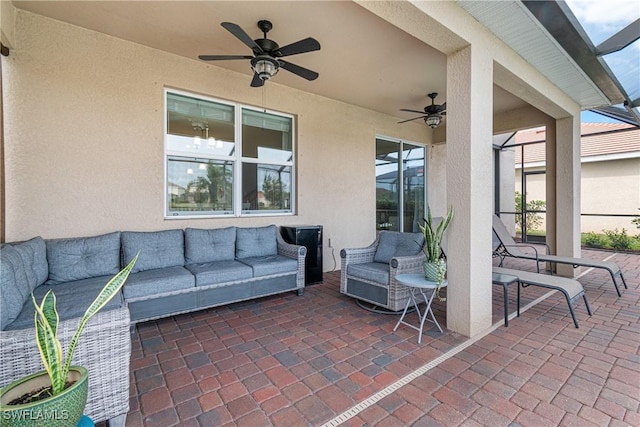 view of patio with an outdoor hangout area, ceiling fan, and glass enclosure