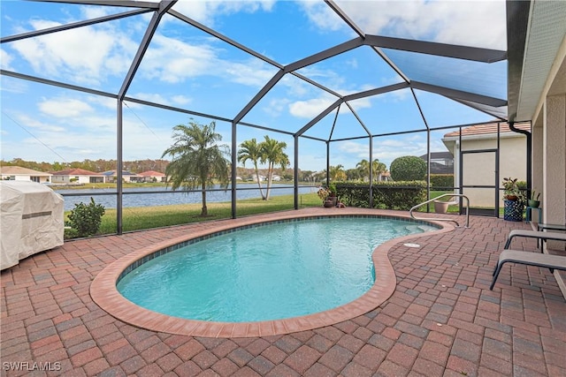 view of pool featuring glass enclosure, a water view, and a patio