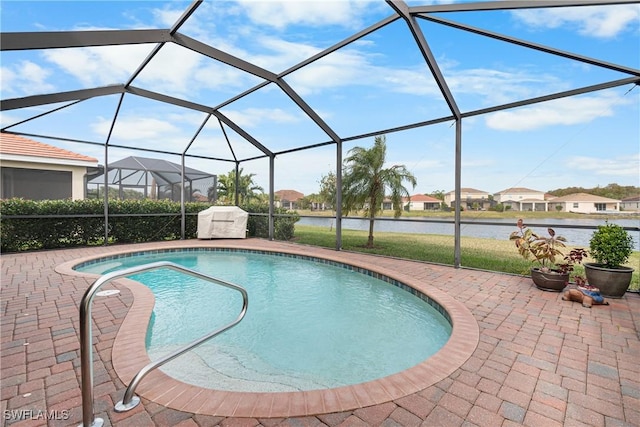 view of swimming pool featuring glass enclosure, a water view, and a patio