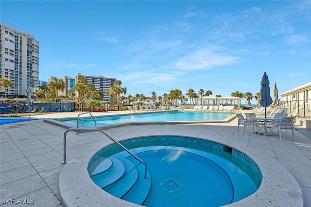 view of pool with a hot tub and a patio