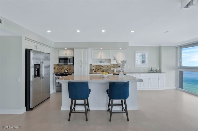 kitchen featuring backsplash, a breakfast bar area, white cabinets, and appliances with stainless steel finishes