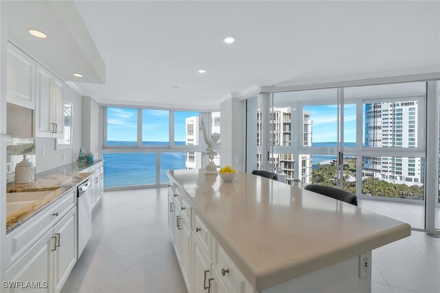 kitchen with white cabinetry, a center island, dishwasher, and a water view