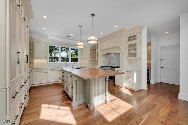 kitchen with high end range, backsplash, a kitchen breakfast bar, and a center island with sink