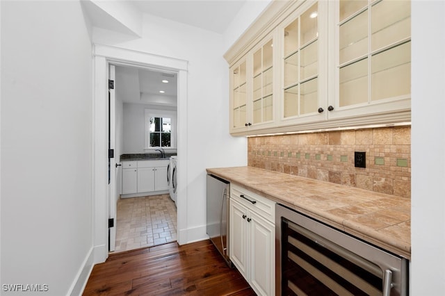 bar featuring sink, refrigerator, washer / dryer, decorative backsplash, and beverage cooler