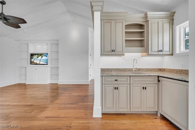 kitchen with sink, vaulted ceiling with beams, ceiling fan, light stone countertops, and light hardwood / wood-style flooring