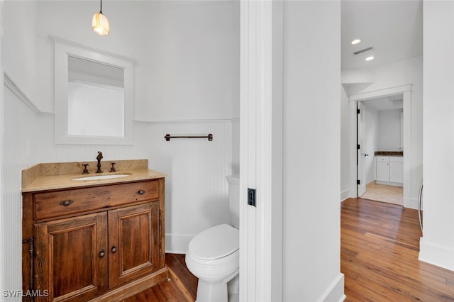 bathroom with hardwood / wood-style flooring, vanity, and toilet