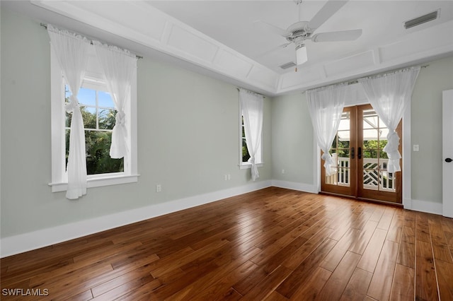 unfurnished room featuring a tray ceiling, hardwood / wood-style floors, ceiling fan, and french doors