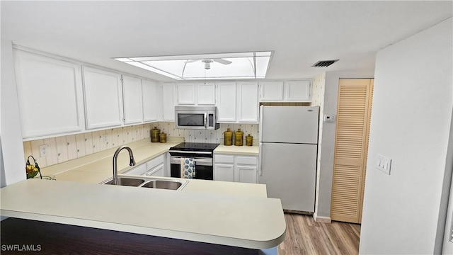 kitchen featuring sink, light wood-type flooring, kitchen peninsula, stainless steel appliances, and white cabinets