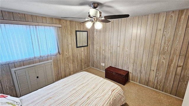 bedroom with carpet flooring, ceiling fan, and wood walls