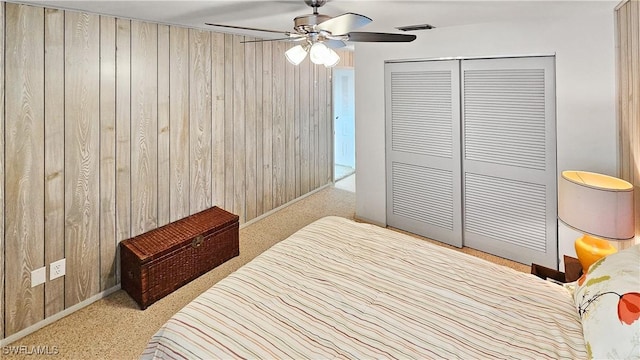 bedroom with a closet, light carpet, and wood walls