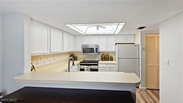 kitchen featuring sink, stainless steel appliances, kitchen peninsula, and white cabinets