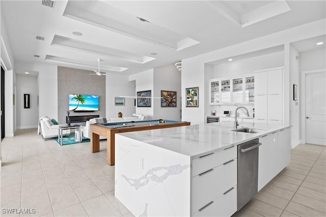 kitchen with white cabinetry, sink, a raised ceiling, and a center island with sink