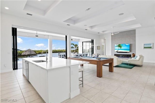 kitchen with a water view, sink, white cabinets, and a tray ceiling