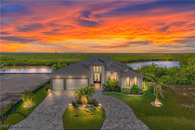 view of front facade with a water view, a garage, and a yard