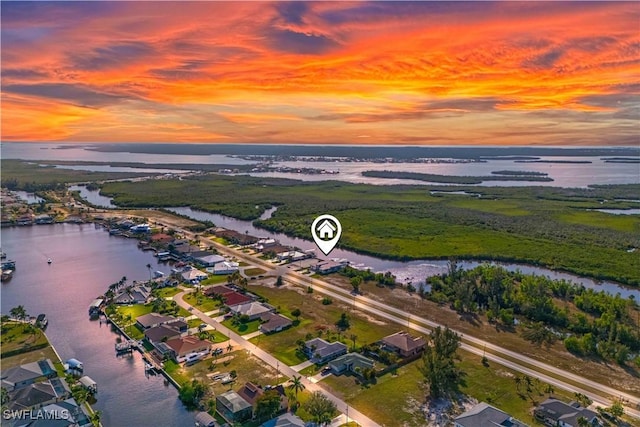 aerial view at dusk featuring a water view