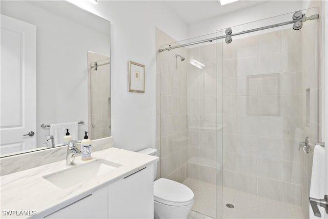 bathroom featuring vanity, toilet, and a shower with door