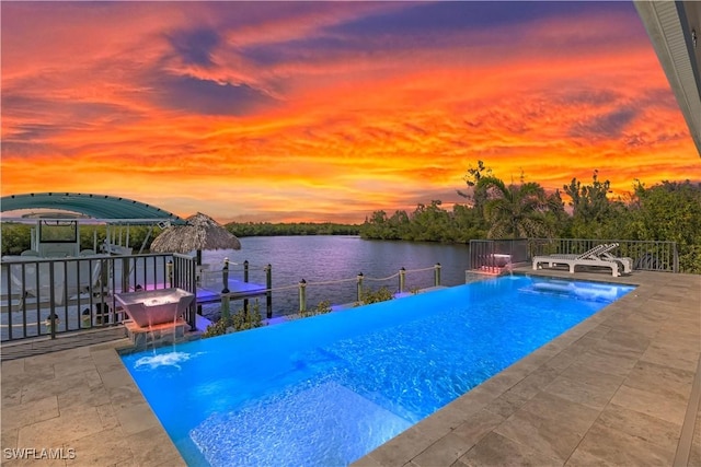 pool at dusk featuring a patio, a water view, and pool water feature