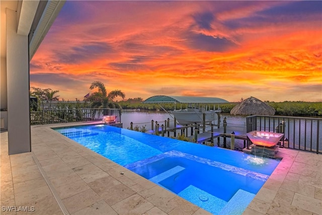 pool at dusk with a water view, an in ground hot tub, and a boat dock