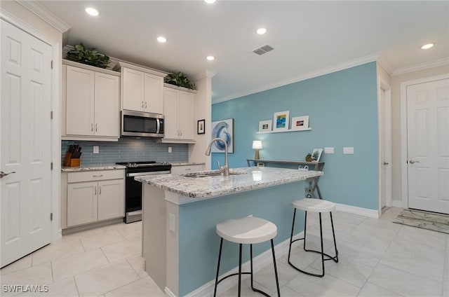 kitchen with sink, a breakfast bar, appliances with stainless steel finishes, a kitchen island with sink, and light stone countertops