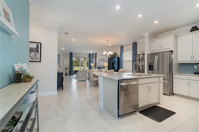 kitchen featuring sink, crown molding, appliances with stainless steel finishes, white cabinetry, and a center island with sink