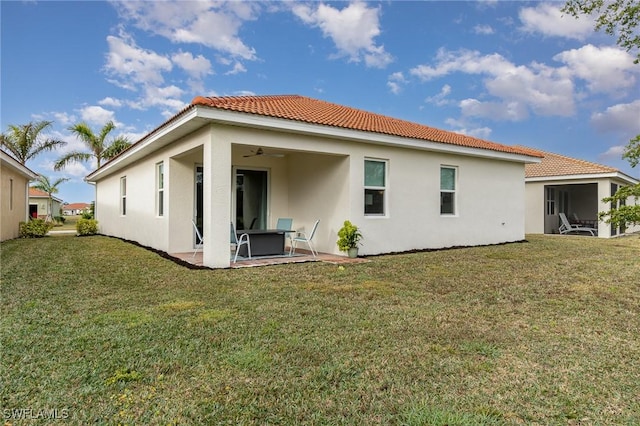 back of house with ceiling fan, a patio area, and a lawn