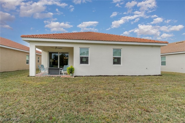 back of property with a yard, a patio, and ceiling fan