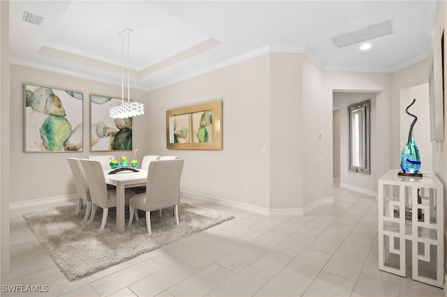 tiled dining area featuring ornamental molding and a tray ceiling