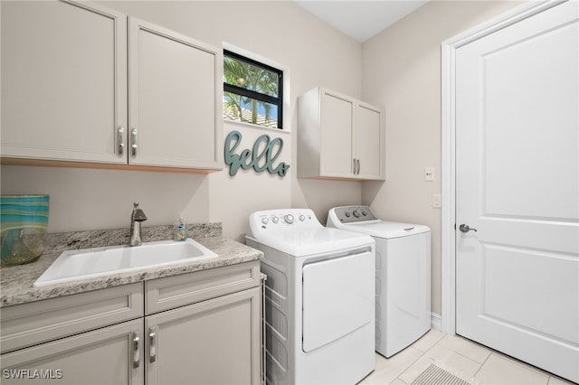 laundry area featuring light tile patterned flooring, cabinets, sink, and washing machine and clothes dryer