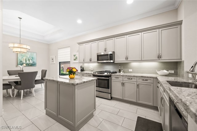 kitchen with light stone countertops, sink, pendant lighting, and appliances with stainless steel finishes