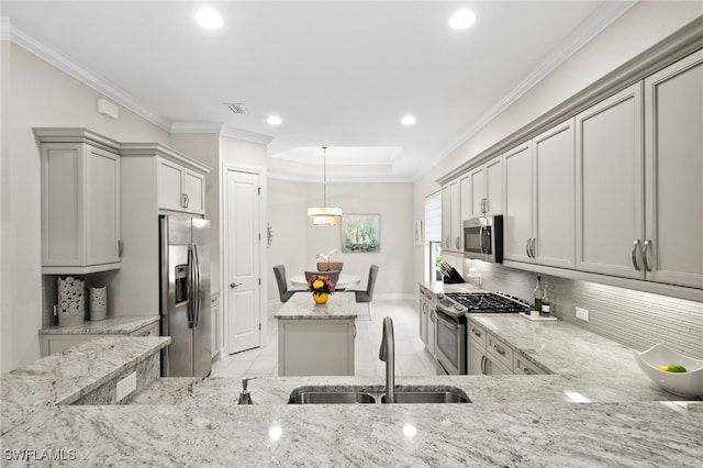 kitchen with gray cabinets, appliances with stainless steel finishes, hanging light fixtures, light stone counters, and sink