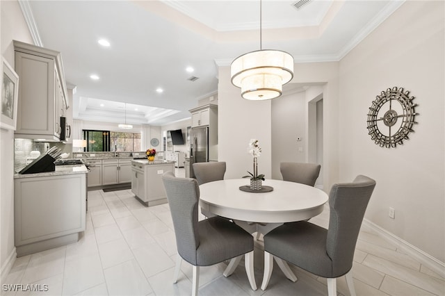 dining space with sink, a tray ceiling, and crown molding