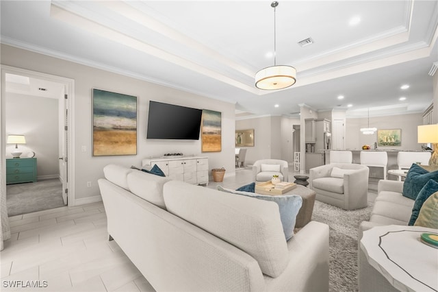 living room with a tray ceiling and ornamental molding