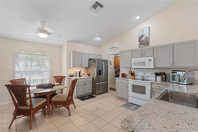 kitchen with light tile patterned flooring, white appliances, sink, vaulted ceiling, and gray cabinetry