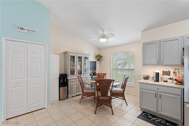 dining room with ceiling fan, vaulted ceiling, and light tile patterned flooring