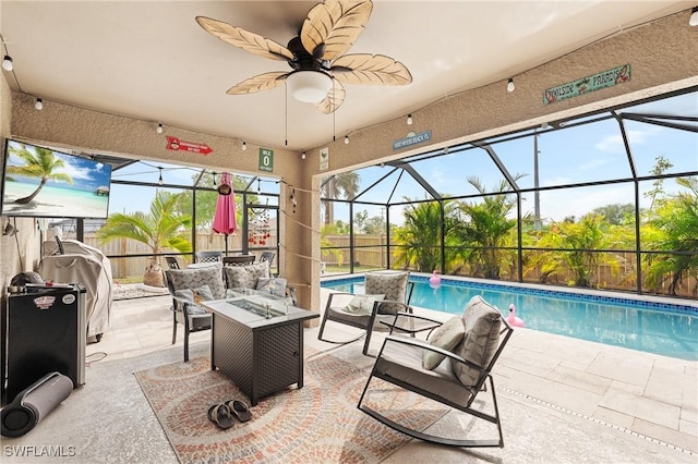 view of pool featuring ceiling fan, glass enclosure, a patio area, and a fire pit