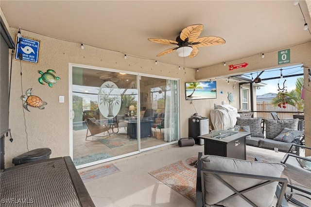 view of patio featuring ceiling fan and an outdoor living space with a fire pit