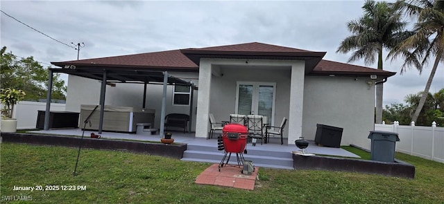 back of property featuring a yard, a hot tub, and a patio