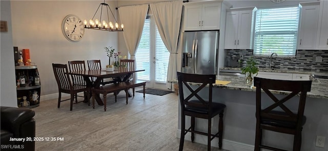 kitchen with light stone counters, white cabinetry, and stainless steel fridge with ice dispenser