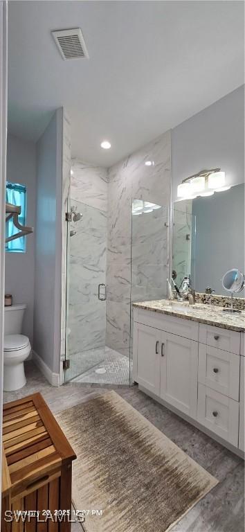 bathroom featuring wood-type flooring, an enclosed shower, vanity, and toilet