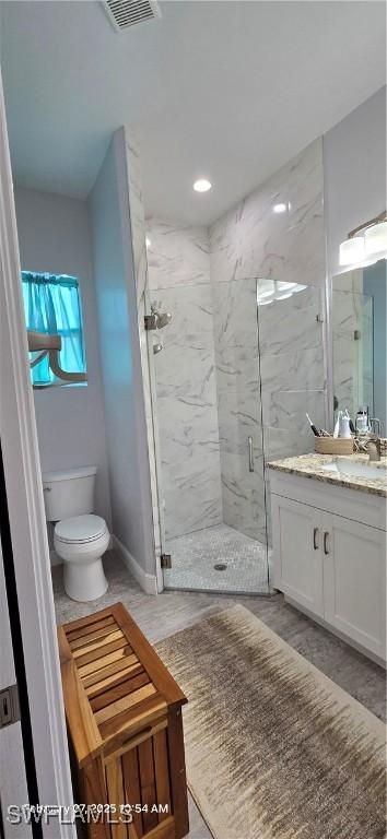 bathroom featuring vanity, toilet, and an enclosed shower