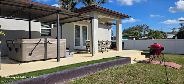 back of house featuring a lawn, a hot tub, and a patio