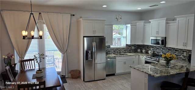 kitchen with sink, white cabinetry, hanging light fixtures, stainless steel appliances, and backsplash