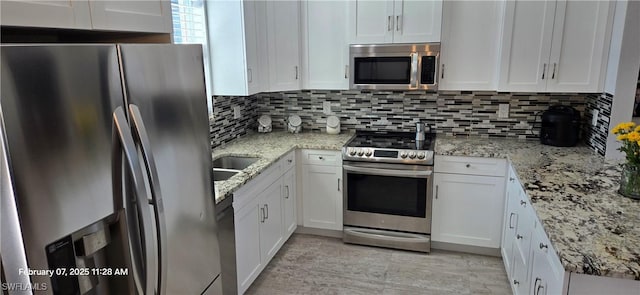 kitchen featuring white cabinetry, light stone counters, decorative backsplash, and appliances with stainless steel finishes