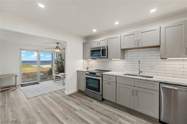 kitchen featuring sink, tasteful backsplash, light hardwood / wood-style flooring, appliances with stainless steel finishes, and gray cabinets