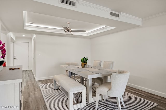 dining room with crown molding, hardwood / wood-style floors, ceiling fan, and a tray ceiling