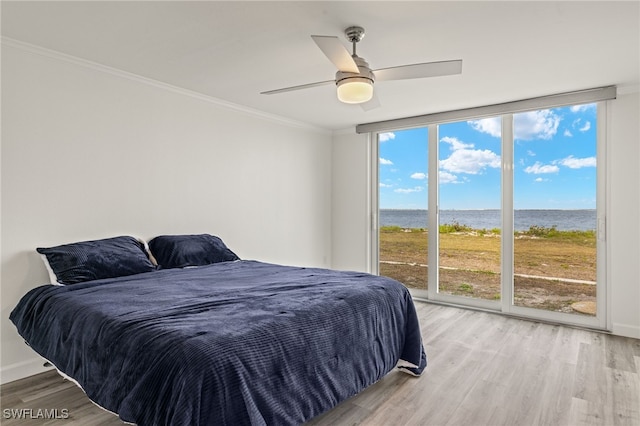 bedroom featuring multiple windows, a wall of windows, access to exterior, ceiling fan, and a water view