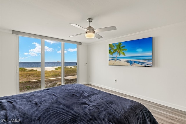 bedroom featuring crown molding, ceiling fan, a water view, wood-type flooring, and access to outside