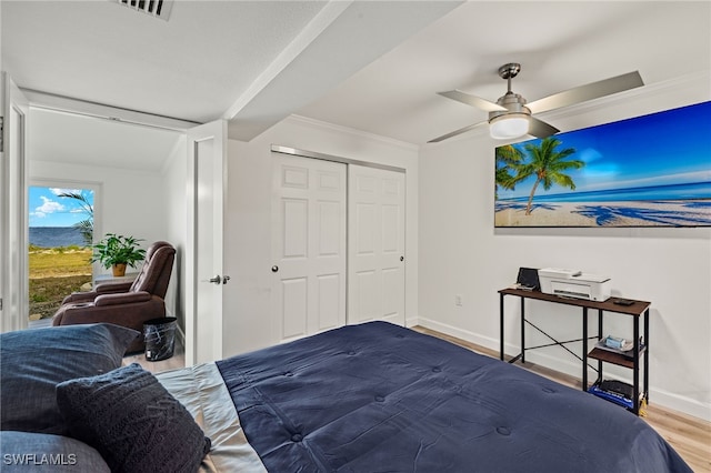 bedroom featuring crown molding, wood-type flooring, a closet, and ceiling fan