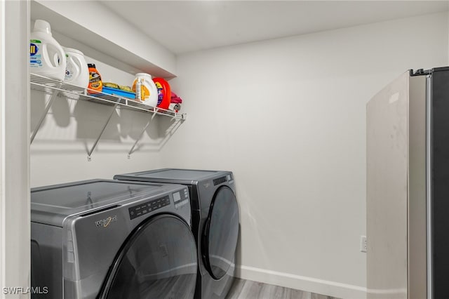 laundry room with hardwood / wood-style flooring and washing machine and clothes dryer